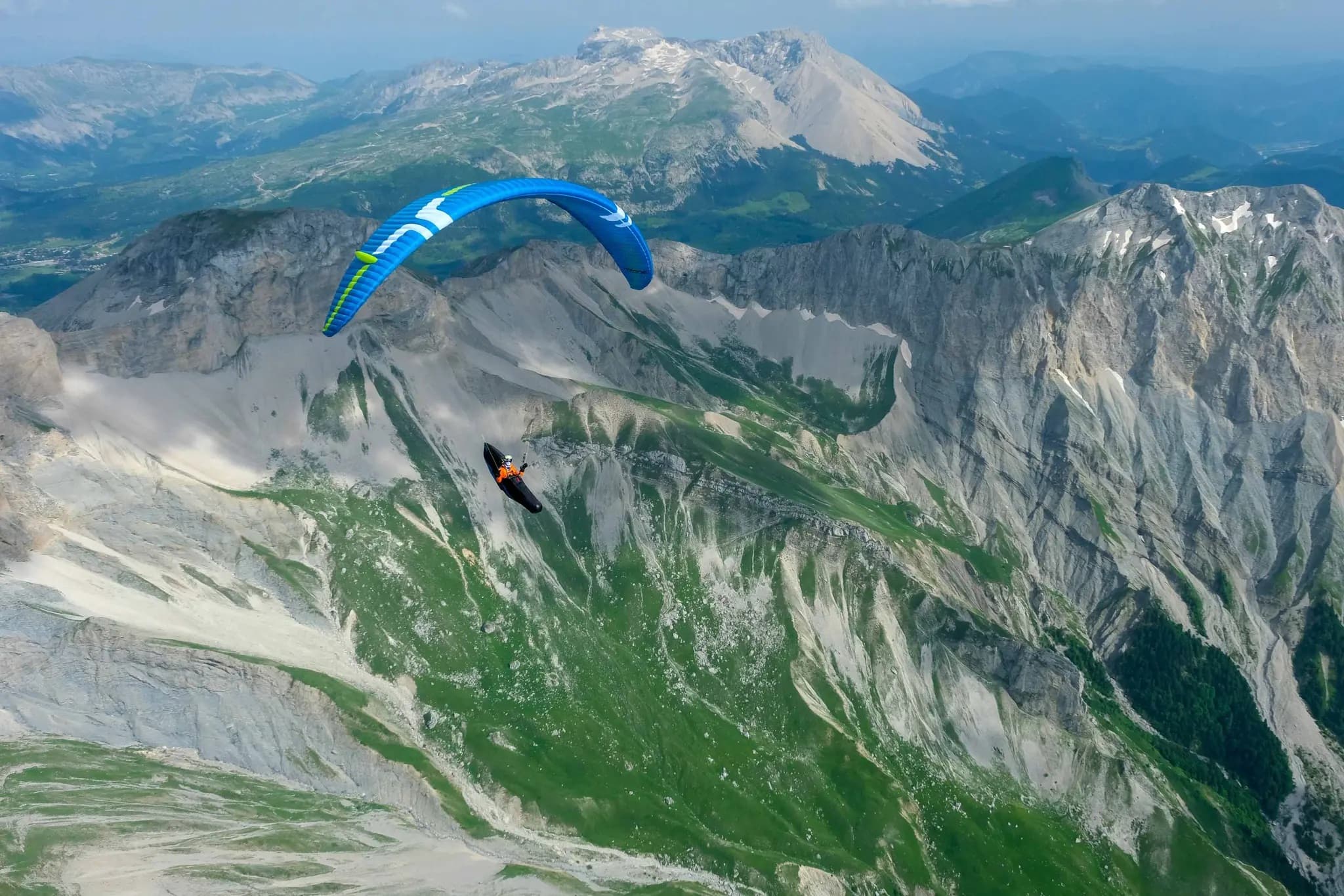 Piloto de parapente voando sobre montanhas